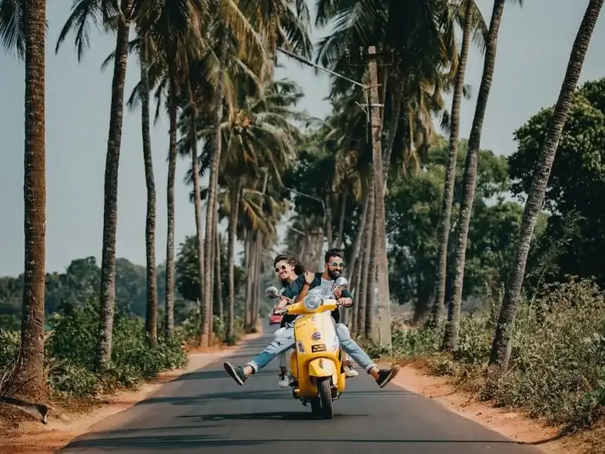 Dos personas en moto por una carretera entre palmeras