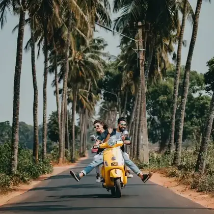 Dos personas en moto entre palmeras